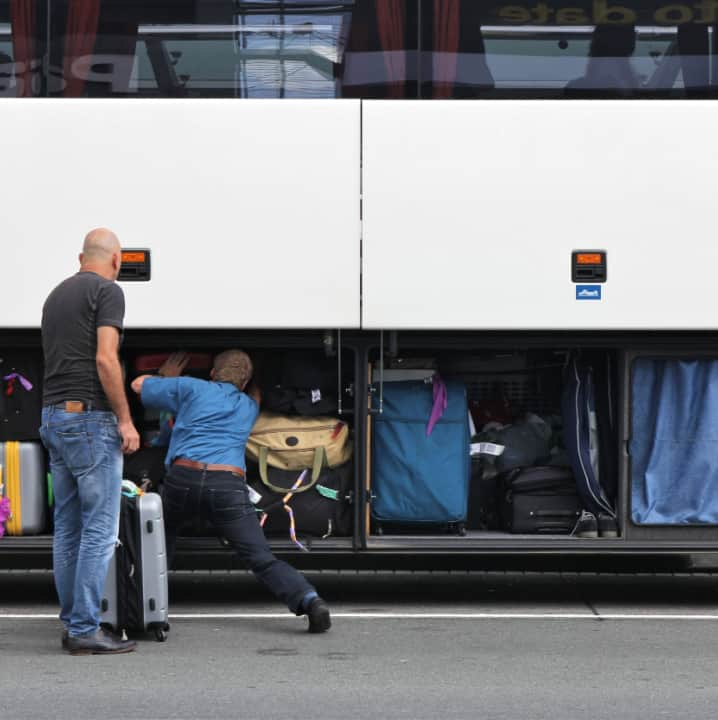 A charter bus driver loading up luggage bays